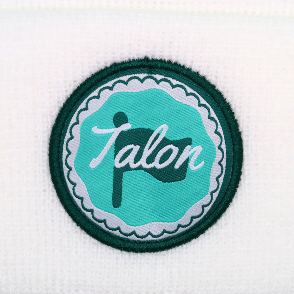 White Knit Beanie with Green and Teal Circle Logo Closeup.