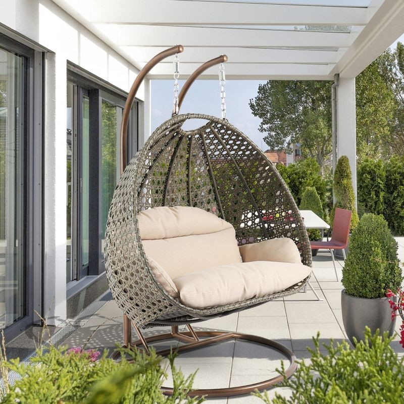 LeisureMod Beige Wicker Hanging 2 person Egg Swing Chair Beige on Patio.