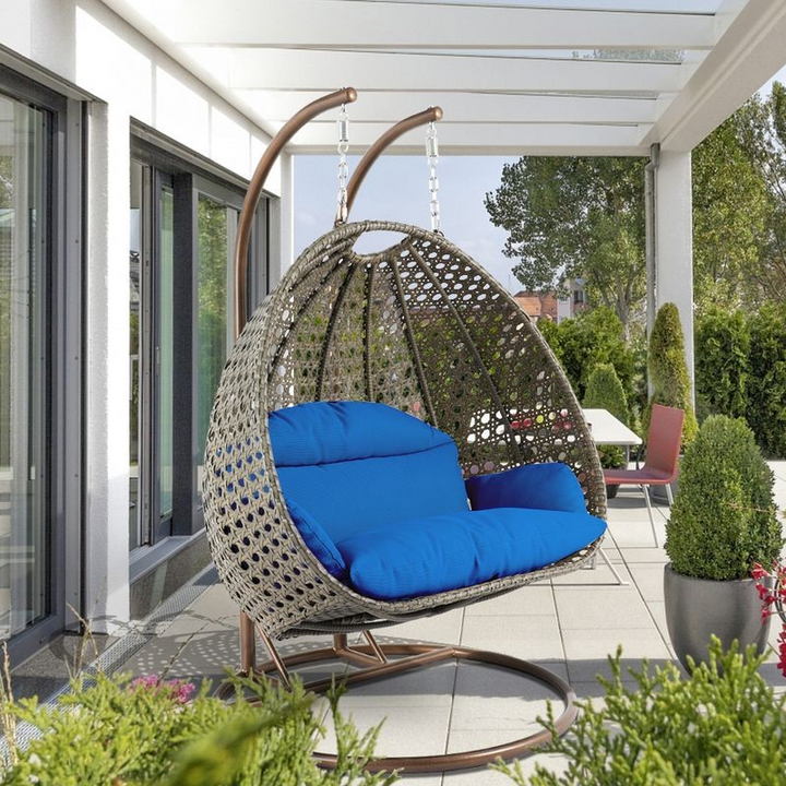 LeisureMod Beige Wicker Hanging 2 person Egg Swing Chair Blue on Patio.
