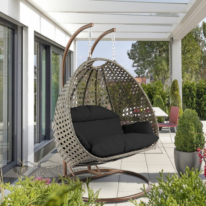 LeisureMod Beige Wicker Hanging 2 person Egg Swing Chair Black on Patio.