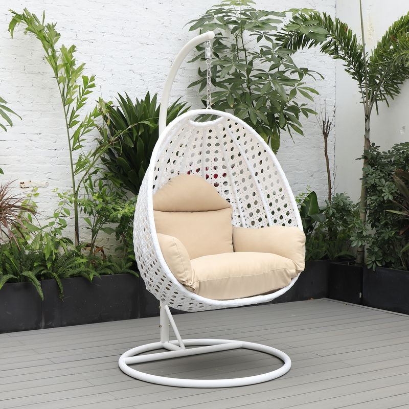 LeisureMod White Wicker Hanging Egg Swing Chair Beige on Patio.