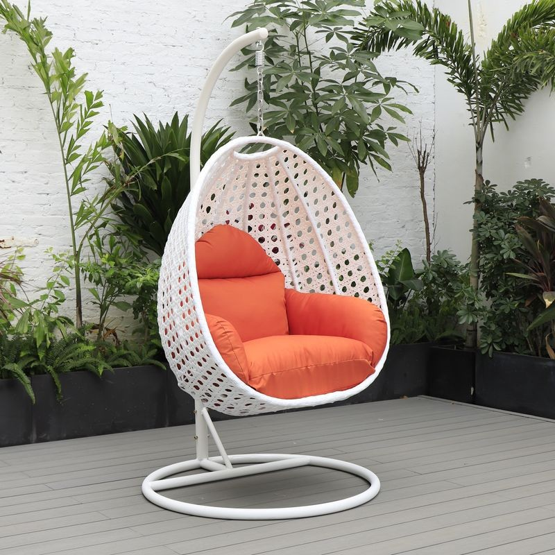 LeisureMod White Wicker Hanging Egg Swing Chair Orange on Patio.
