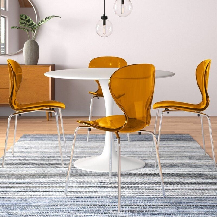 LeisureMod 5-Piece Dining Set Round White MDF Dining Table and 4 Plastic Dining Chairs with Chrome Legs Transparent Orange in Room.