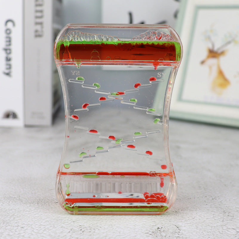 Clear container with colorful liquid levels on a light surface.