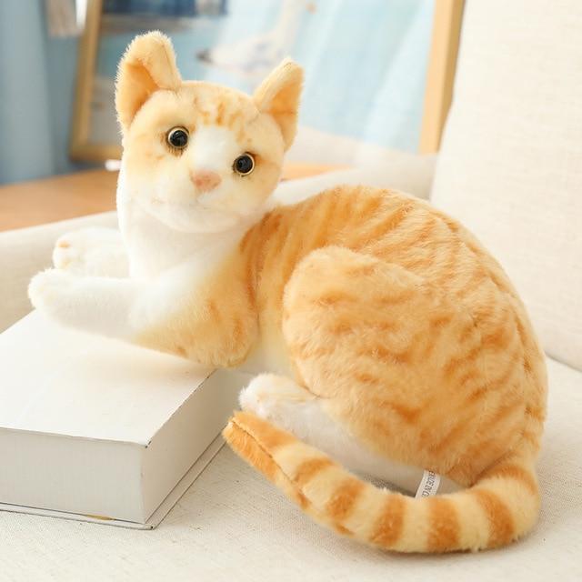 Plush toy cat sitting on a white surface with a blurred background.