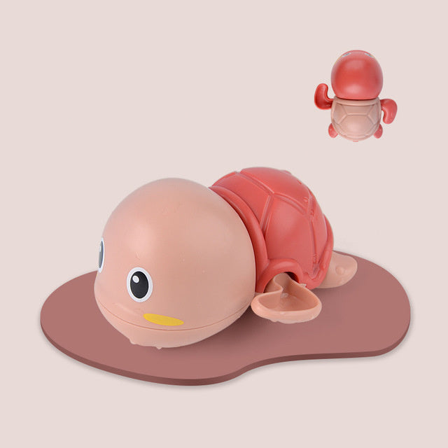 Toy turtle with a pink shell on a beige background.
