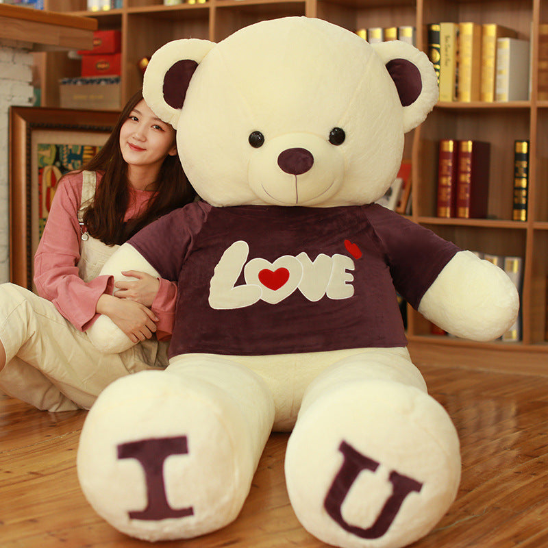 Large white teddy bear with a LOVE shirt held by a person in a room with bookshelves.