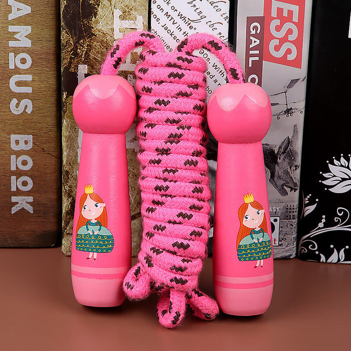 Pink skipping rope with cartoon character handles on a brown surface.