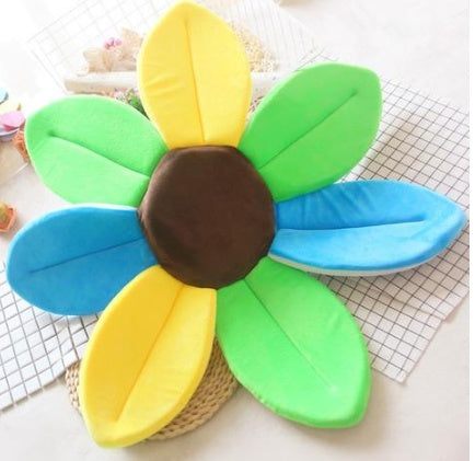 Colorful flower shaped cushion with yellow, green, blue, and brown petals on a checkered background.