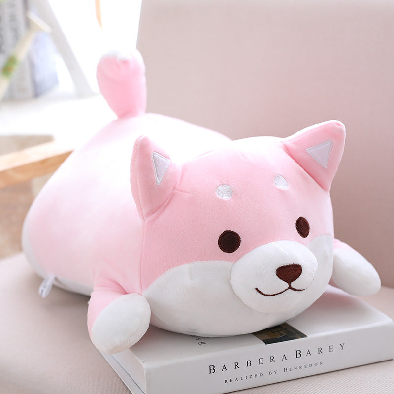 Cute pink and white plush toy resembling a dog on top of a book.