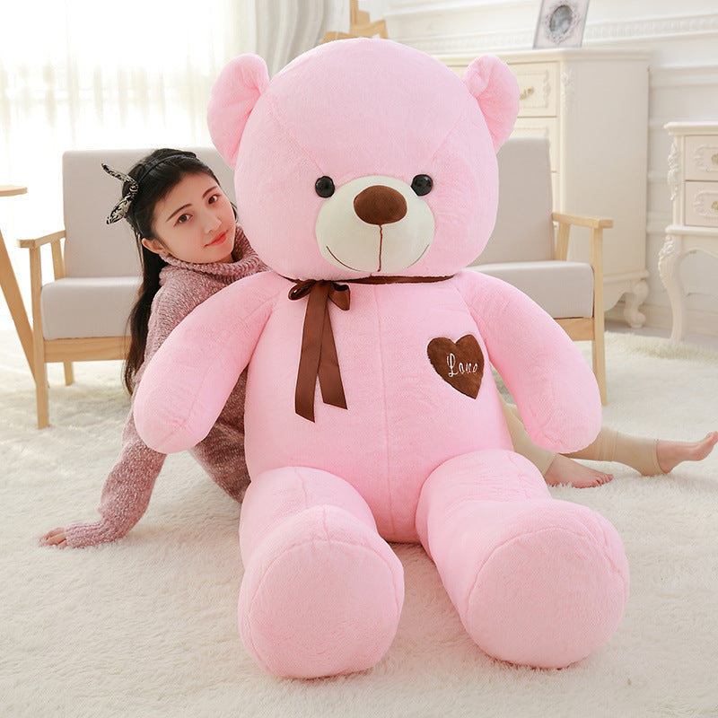 Person holding a large pink teddy bear in a room with light-colored furniture.
