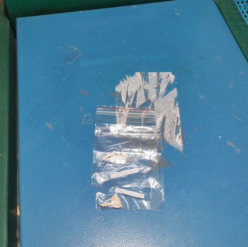 Small clear plastic bag with items on a blue surface.