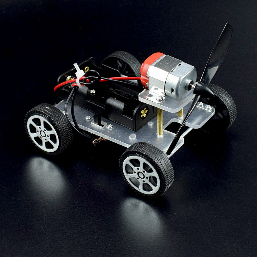 Small model car with wheels, motor, and propeller on a black background.