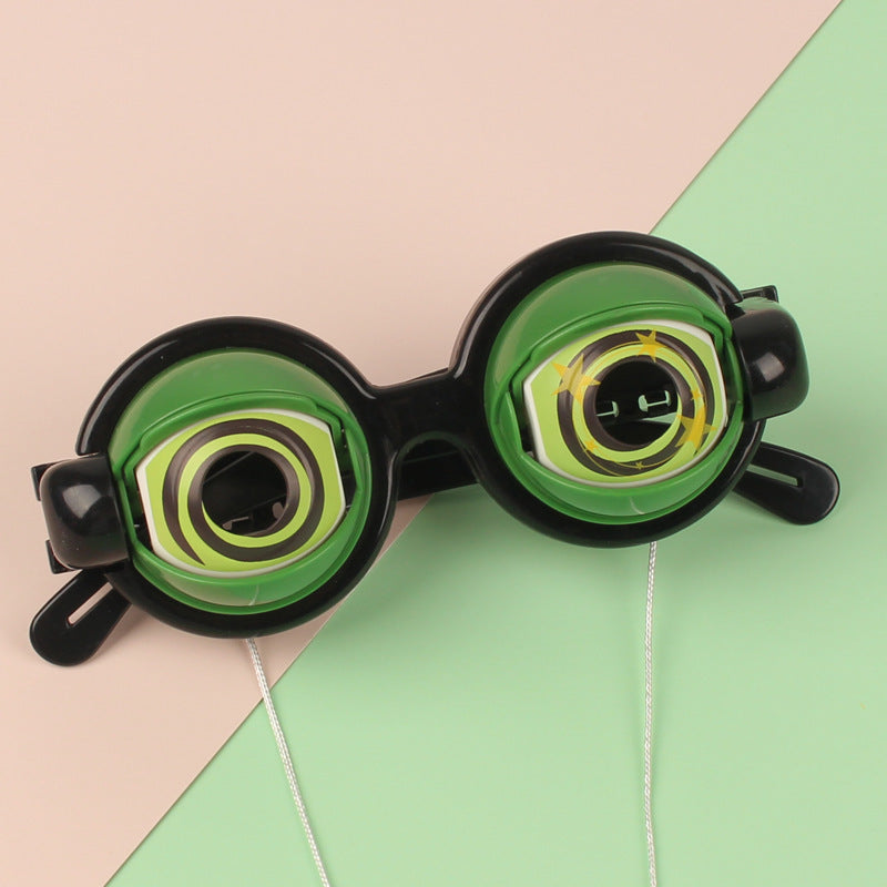 Black goggles with green lenses on a pink and green geometric background.
