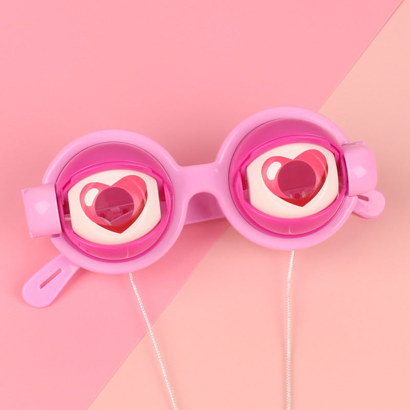 Pink goggles with heart designs on a pink background.