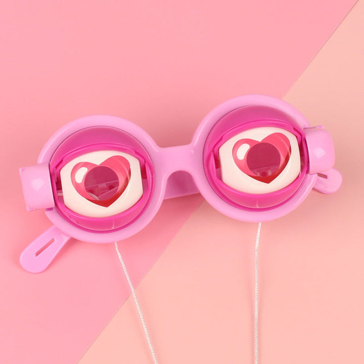 Pink goggles with heart designs on a pink background.