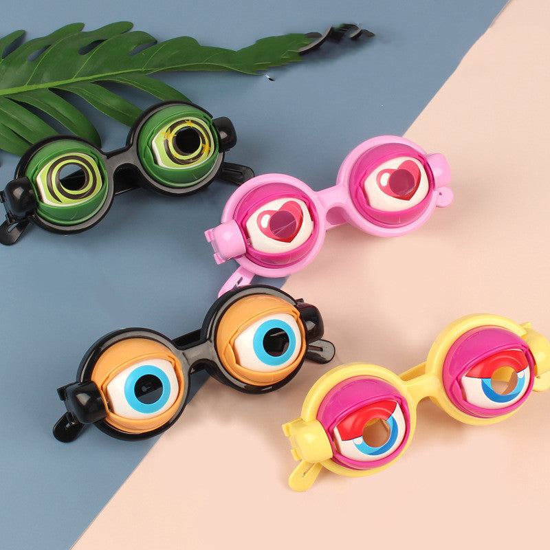 Colorful novelty goggles on a person's wrist with a blue background and green leaf.