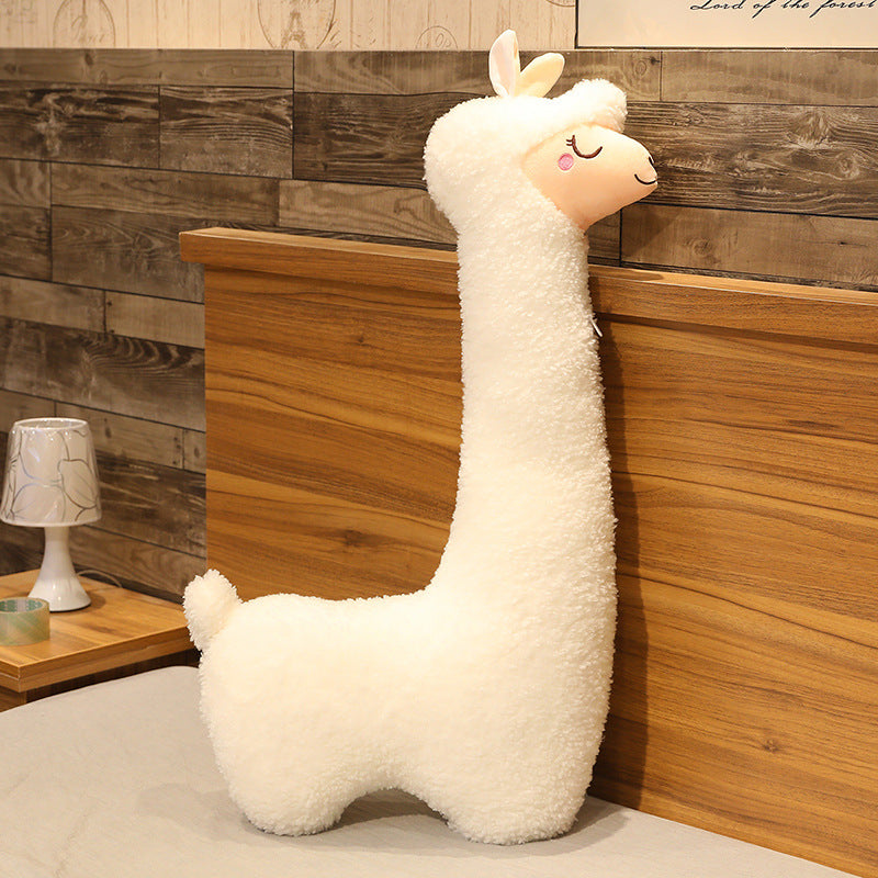White plush llama toy on a wooden shelf with a wooden wall background.