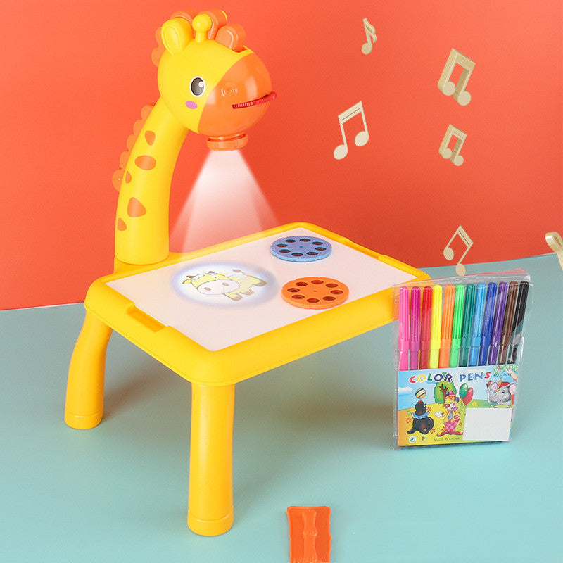 Yellow toy giraffe with a table and projector, next to colored pencils on a teal surface with an orange background.