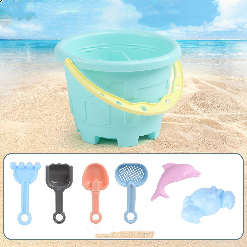 Blue sand bucket with yellow handle on a sandy beach, accompanied by various sand toys.