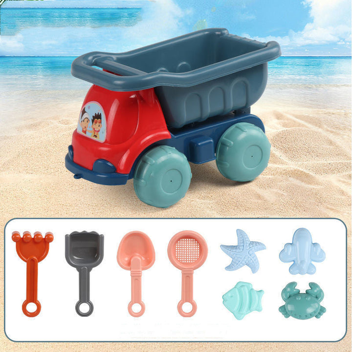 Toy dump truck with sand tools on a sandy beach background.