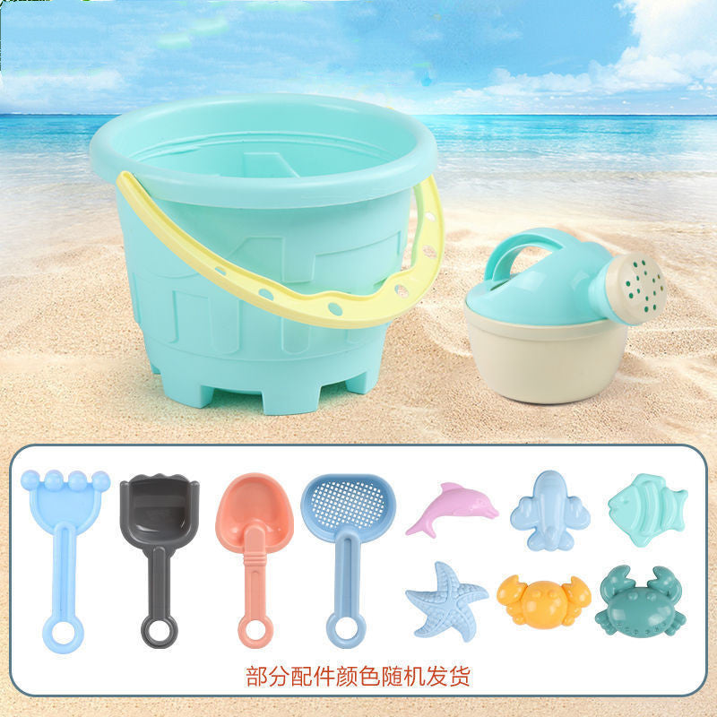 Children's sand toys including a bucket and spade set on a sandy beach with ocean view.