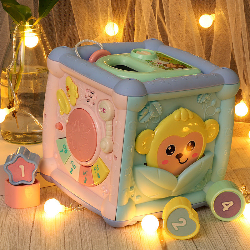 Children's toy cube with monkey design on a wooden surface with decorative lights.