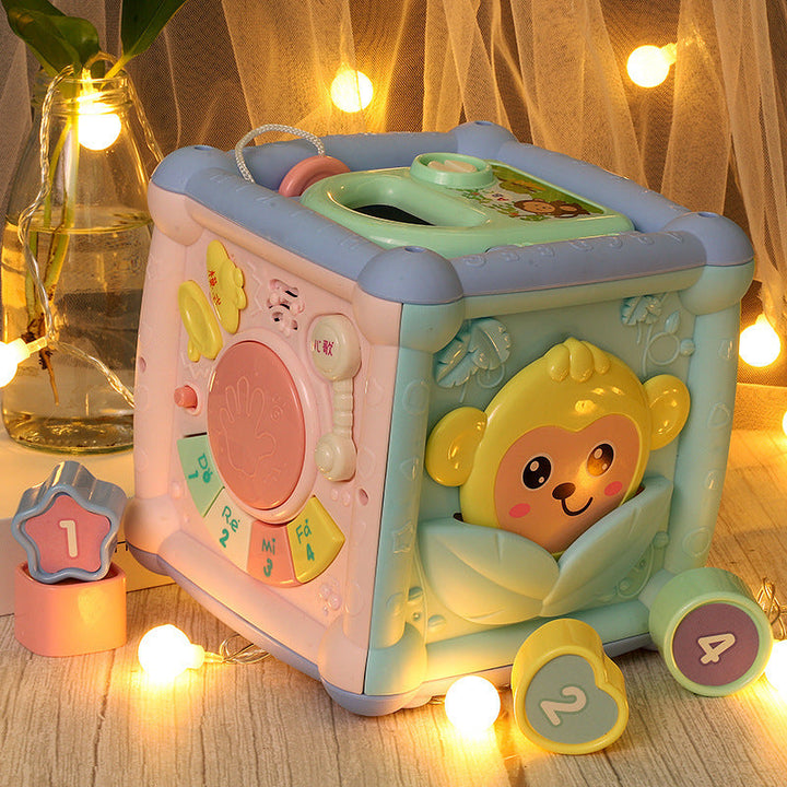 Children's toy cube with monkey design on a wooden surface with decorative lights.