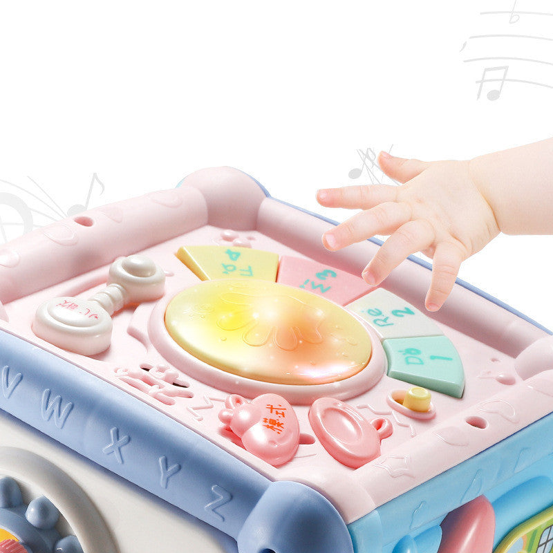 Children's toy with various interactive elements and a hand reaching towards it.