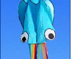 Blue kite with rainbow tail against a blue sky.