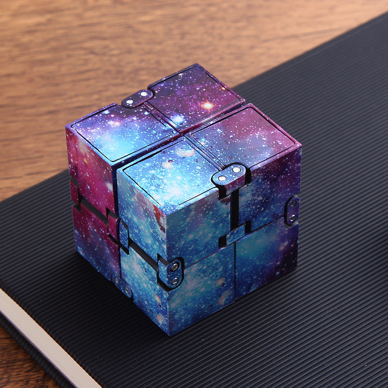 Colorful galaxy themed fidget cube on a dark surface.