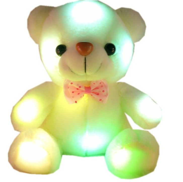 Glowing teddy bear with a pink bow on a white background.