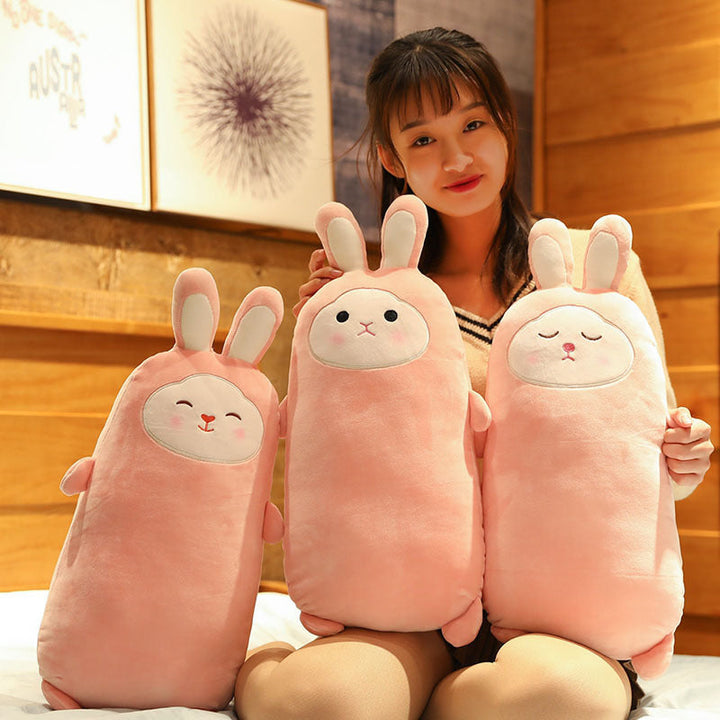 Woman holding three pink rabbit-shaped plush toys in a room with wooden walls.