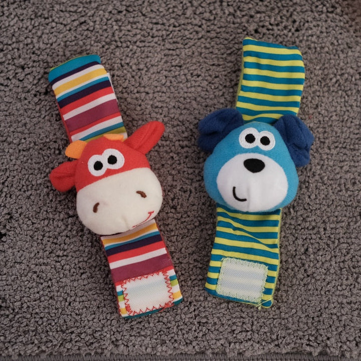 Two colorful baby rattle toys with animal faces on a textured surface.