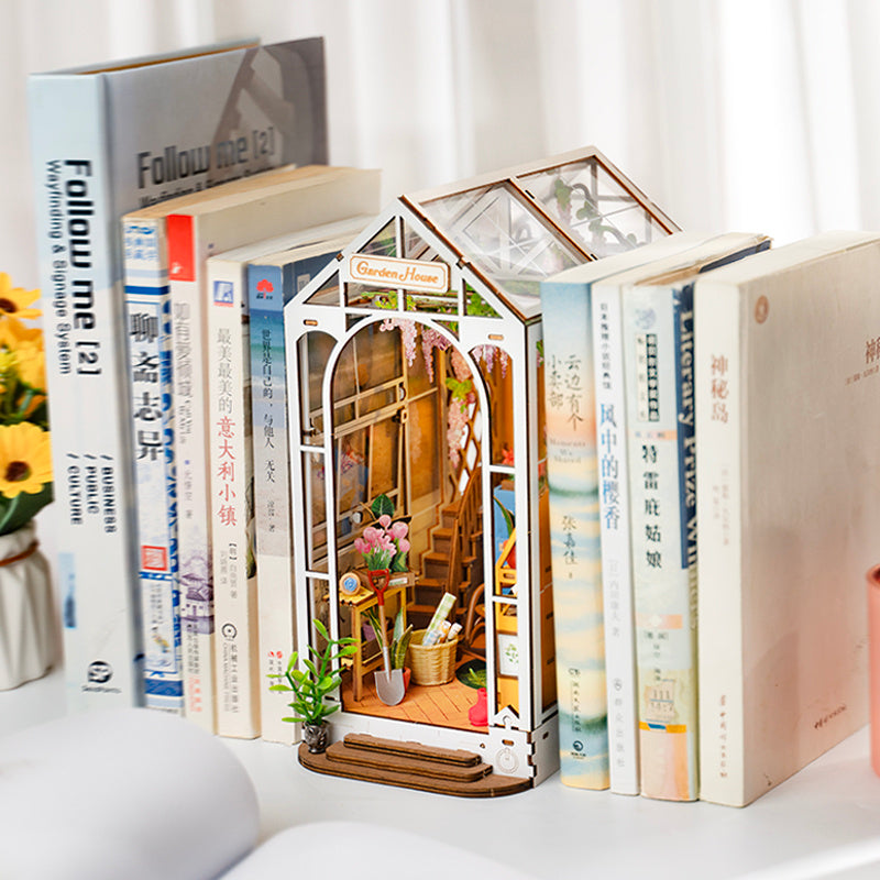 Miniature model of a house built into books with a decorative interior.