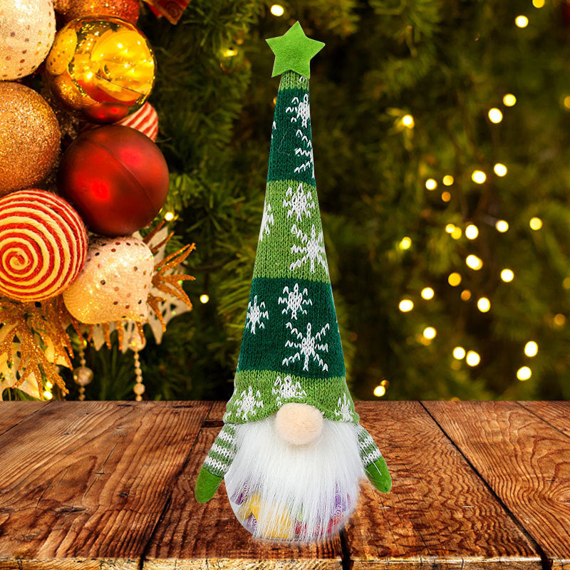Decorative Christmas gnome with green hat and white beard on a wooden surface with festive background.