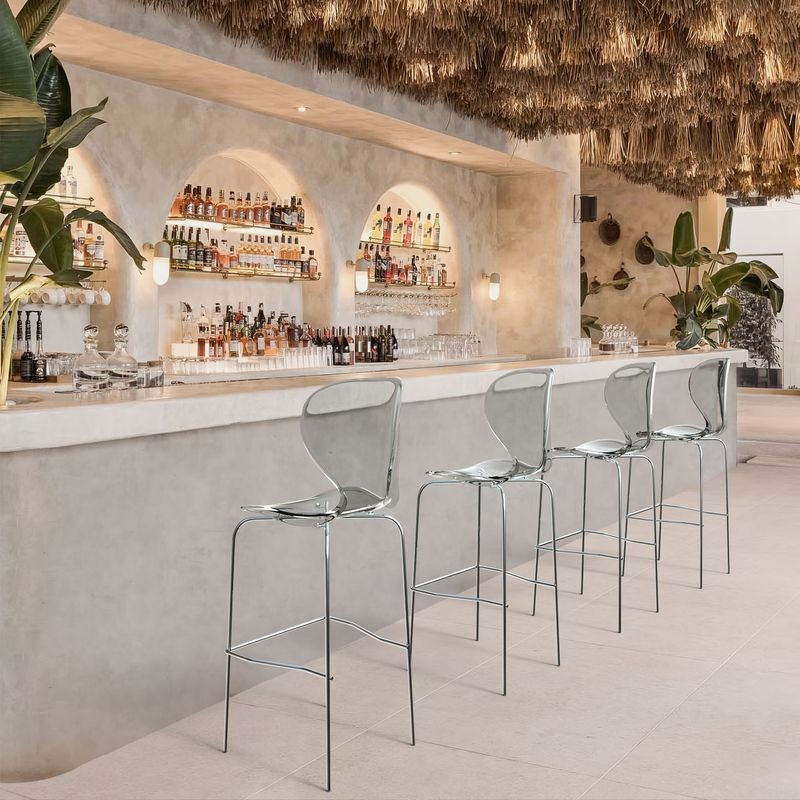 LeisureMod Oyster Acrylic Barstool with Steel Frame in Chrome Finish in Smoke at Bar.