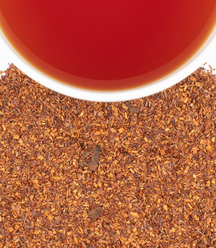 Close-up of a cup of black tea with tea leaves on a white background.