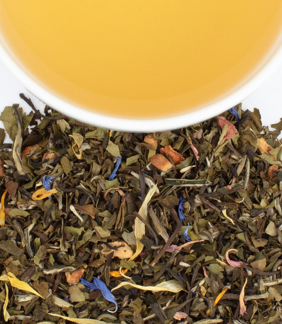 Tea leaves with a cup of tea in the background.