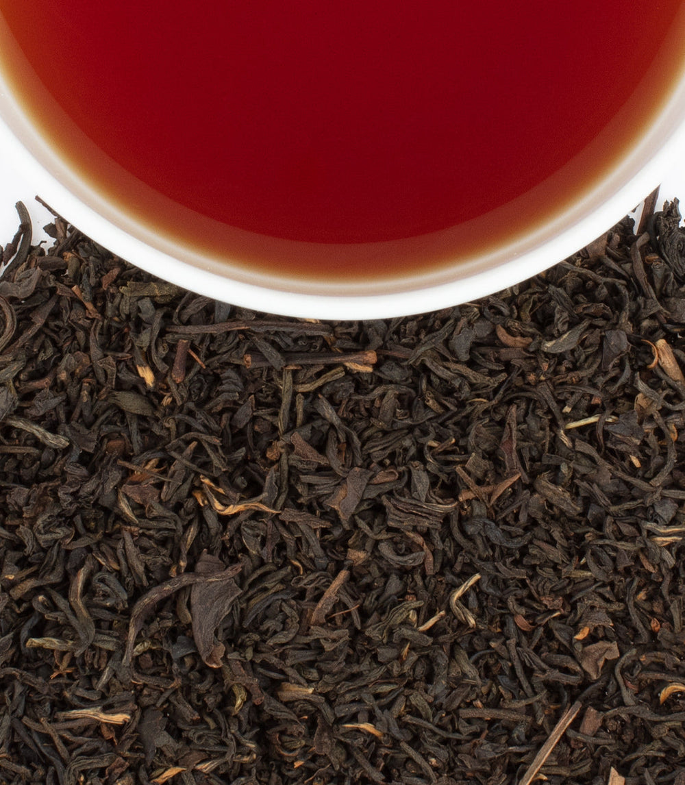 Close-up of tea leaves with a cup of tea in the background