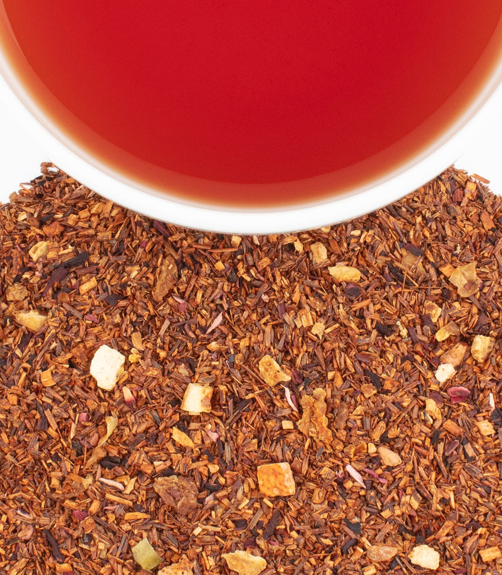 Close-up of dried tea leaves with a cup of tea in the background.