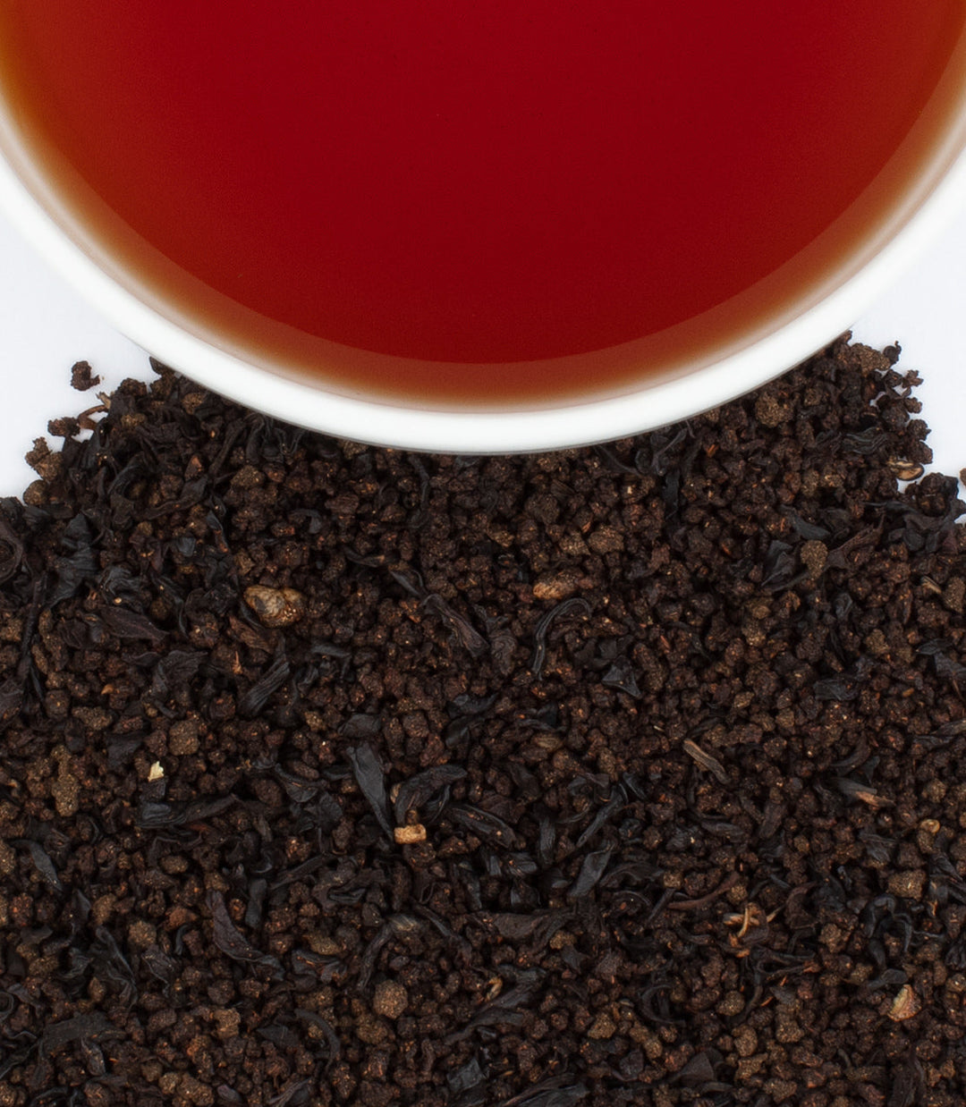 Close-up of tea leaves with a cup of tea in the background