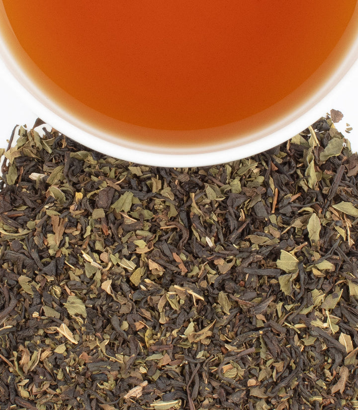 Dry tea leaves and a cup of tea with a close-up view.
