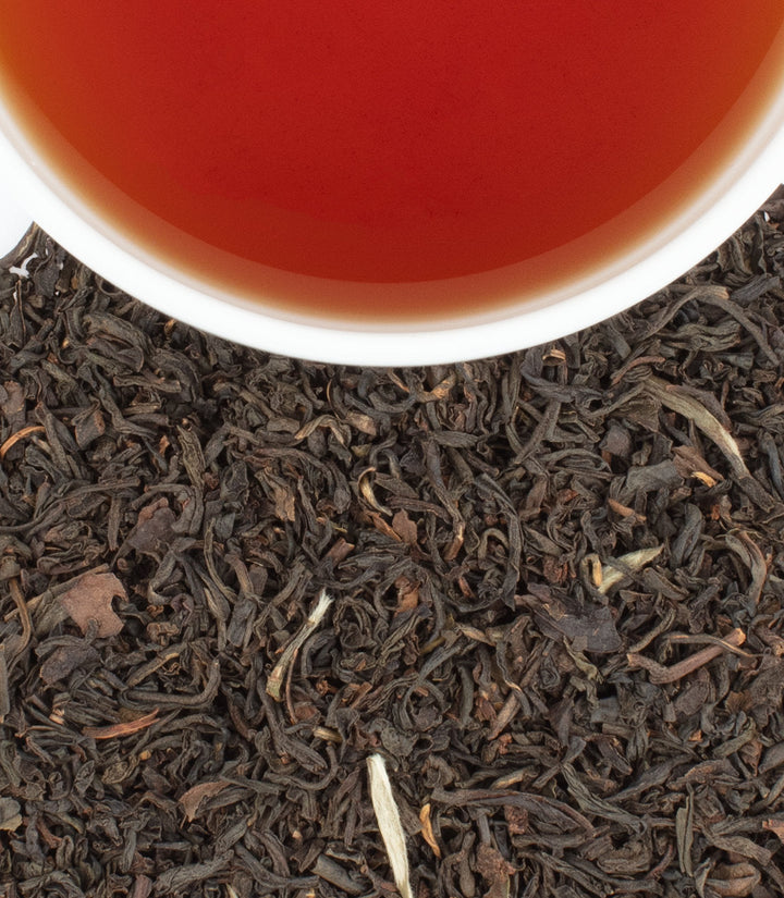 Close-up of tea leaves with a cup of tea in the background