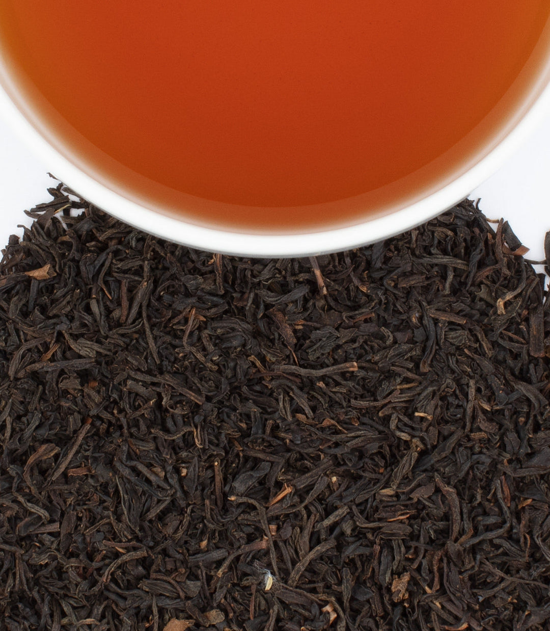 Close-up of tea leaves with a cup of tea in the background.