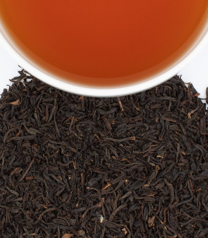 Close-up of tea leaves with a cup of tea in the background.