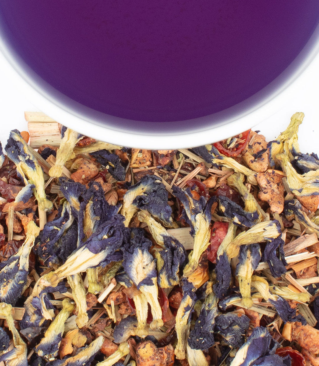 Assorted dried tea leaves with a purple cup in the background.
