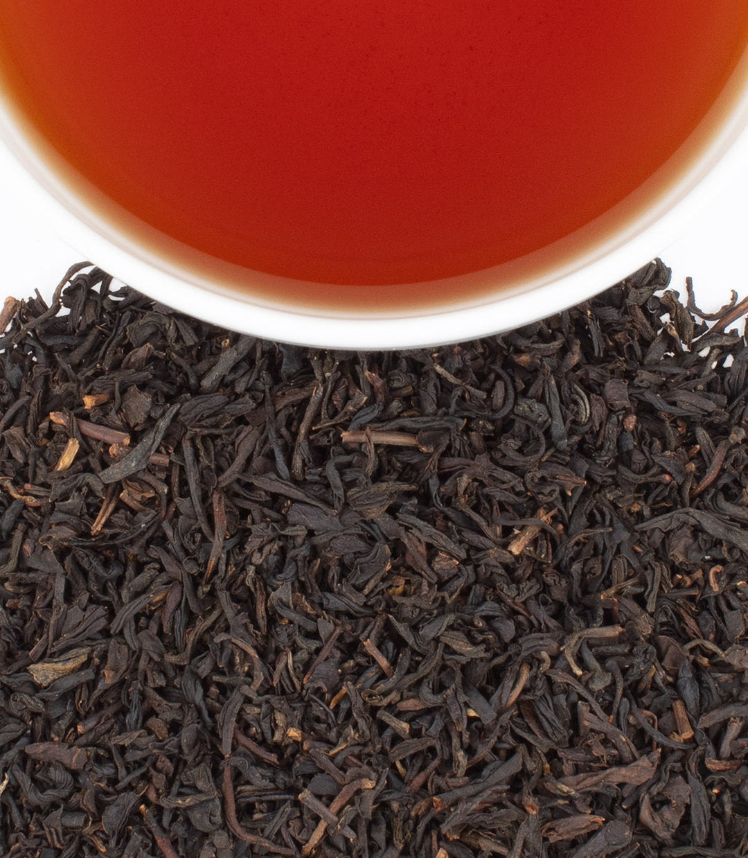 Close-up of tea leaves with a cup of tea in the background