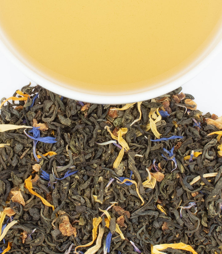 Tea leaves with floral elements and a cup of tea in the background