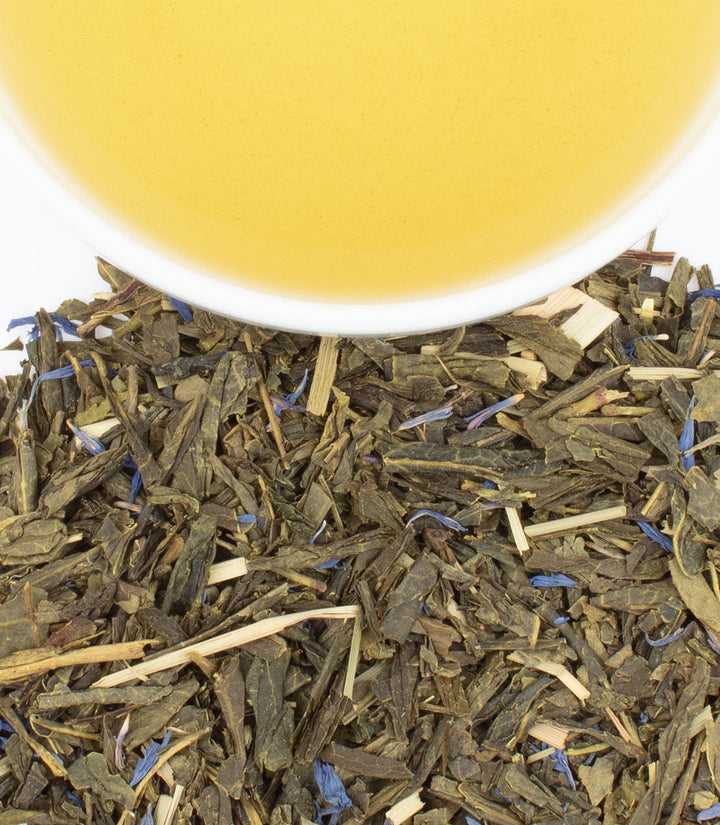 Tea leaves with a cup of tea in the background